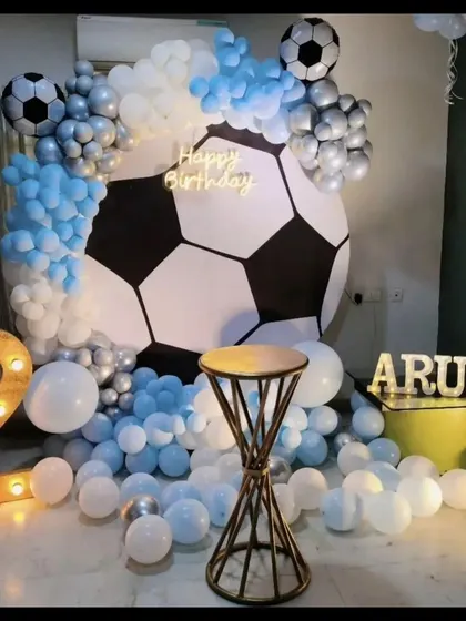 A goal-worthy celebration for a football fan. This soccer-themed decor features a giant football backdrop, light-up numbers, and a balloon arrangement in team colors.