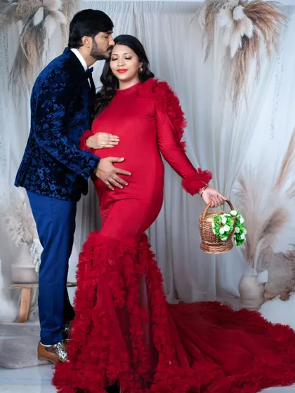 A romantic maternity portrait where the father-to-be kisses his partner's forehead as she holds a small basket.