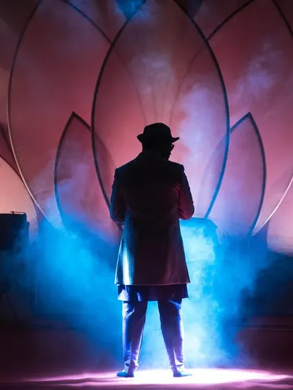 A performer silhouetted against the stage lights, creating a dramatic and mysterious image.