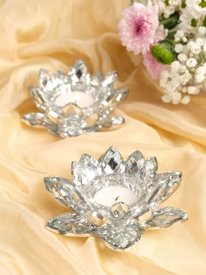 Crystal lotus-shaped tea light holders on a soft, flowing fabric, creating a delicate and serene festive mood.