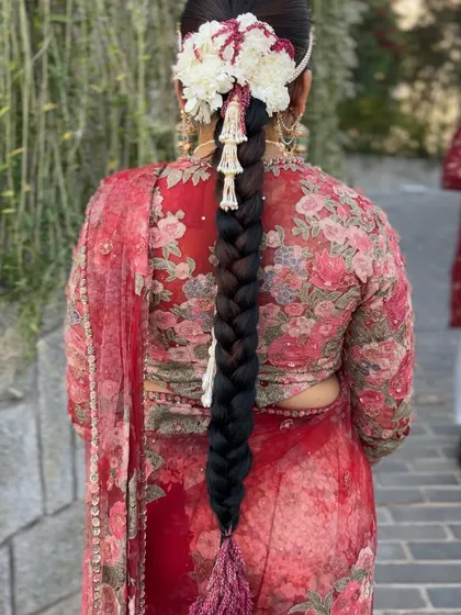 A close up of the traditional braid with a large floral headpiece, showing the intricate details of the flower arrangement and jewellery.