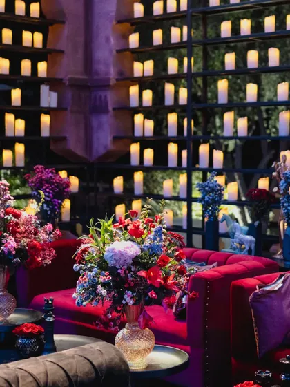 A lounge area at the Jaisalmer reception, with plush red velvet sofas set against a wall of glowing candles, creating a warm and luxurious seating nook.