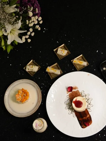 A beautiful flatlay of our dessert offerings. This image showcases a variety of our sweets, from a plated cheesecake and fruit tart to delicate Indian mithai, highlighting our range and artistry.