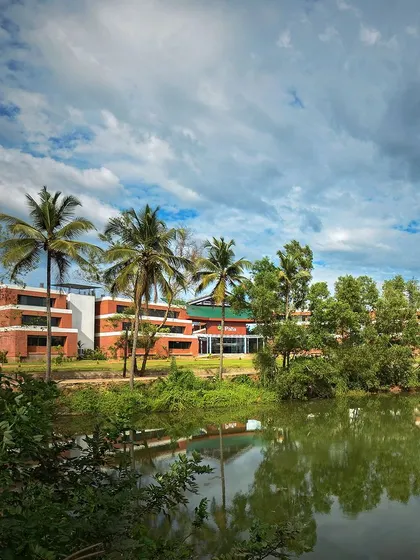 The Pana Global School in Mangalore, viewed from across the adjacent lake. The campus is designed to harmonize with its natural setting, providing students with an inspiring and tranquil environment for learning.