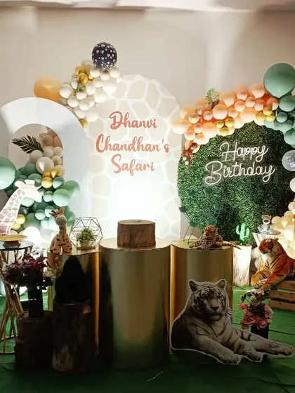 A sophisticated safari theme for Dhaanvi Chandhan's party. This setup uses gold pedestals, a faux grass wall, and realistic animal props for a touch of jungle elegance.