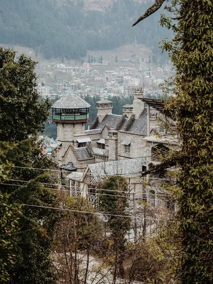 A view of a castle-like building in Manali, peeking through the trees. The architecture in these hill stations often has a unique, old-world charm.