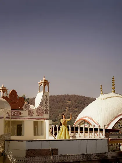 A breathtaking wide shot of the bride Muskan on a palace rooftop, showcasing the stunning architecture and landscape of the venue.