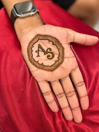 A classic groom's henna design. The bold initials in the center of the palm are a timeless way to celebrate the union.