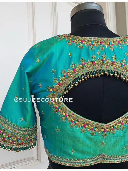 A colorful and festive back design. This teal blouse has a keyhole cutout adorned with multi-colored embroidery and a fringe of delicate gold bead tassels.