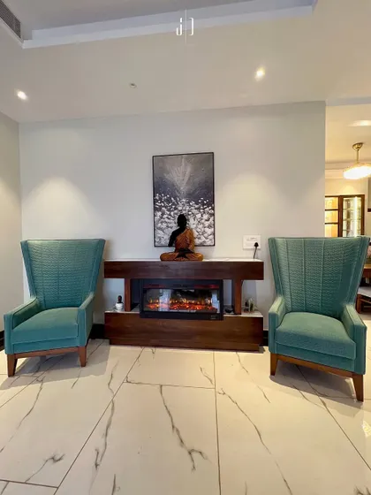 This seating arrangement around the fireplace uses high-back chairs to create a sense of enclosure and intimacy. The Buddha statue adds a touch of tranquility to the space.