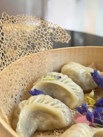 Elegance in a steamer. Our delicate dim sum are presented in a traditional bamboo basket, garnished with edible flowers and served alongside a crispy lattice wafer for added texture.