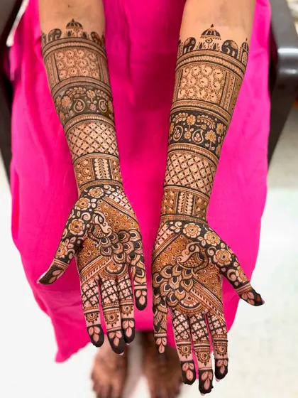 A classic full bridal mehendi with dense, intricate patterns covering the hands and arms.