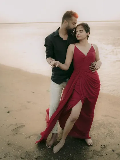 An intimate embrace on the sand, with the warm light of the sunset creating a romantic glow.