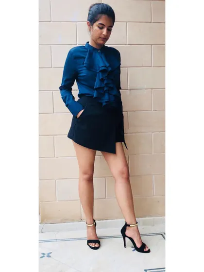 Style is your secret weapon to stand and deliver in a competitive world. This look, featuring a structured ruffle shirt and an asymmetrical skort, creates a powerful silhouette that is both professional and chic.