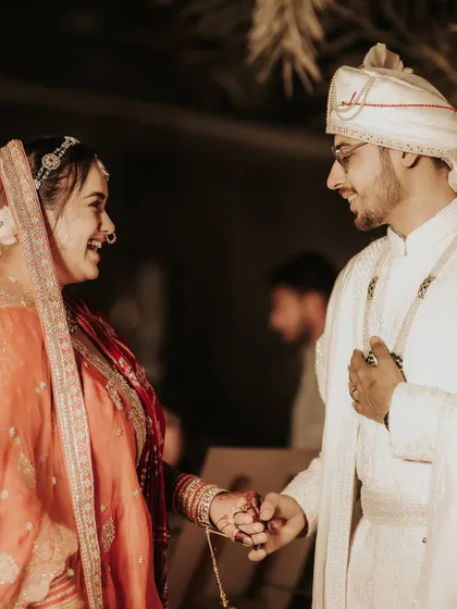 A quiet, candid moment of connection. The bride and groom share a laugh and a gentle touch, a small, authentic interaction that speaks volumes about their relationship.