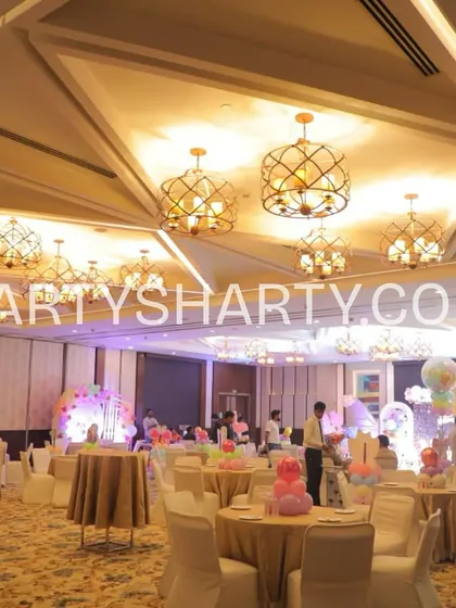 A wide shot of a party venue before guests arrive, showing pastel-themed table settings and balloon decor, highlighting our comprehensive event setup.