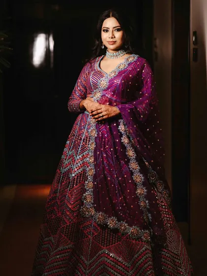 A stunning solo portrait of the bride in her vibrant purple sangeet lehenga, looking confident and beautiful.