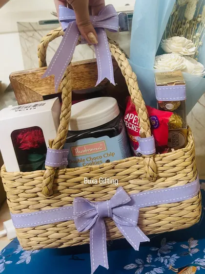 A hand holding the lilac-themed birthday hamper, showing its generous size and beautiful arrangement.
