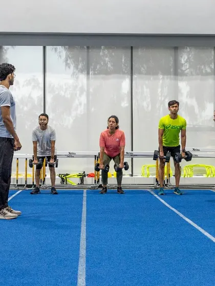 Our coach oversees a group performing deadlifts, ensuring correct technique and posture. This exercise is crucial for developing the posterior chain muscles essential for running.