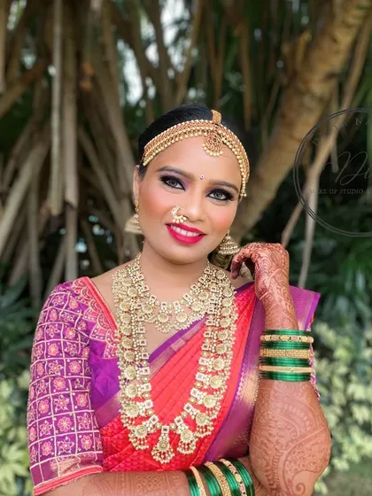 A full smile from a happy bride. Her complete look, including the green bangles that contrast with her pink saree, shows how every detail comes together. The makeup is designed to last all day and look perfect from every angle.