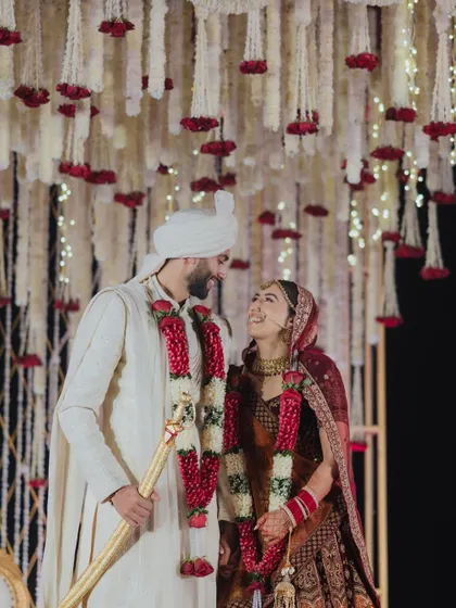 The couple shares a look of love under a canopy of flowers. I focus on creating decor that enhances the romance of the moment, like this beautiful floral installation that frames them perfectly.