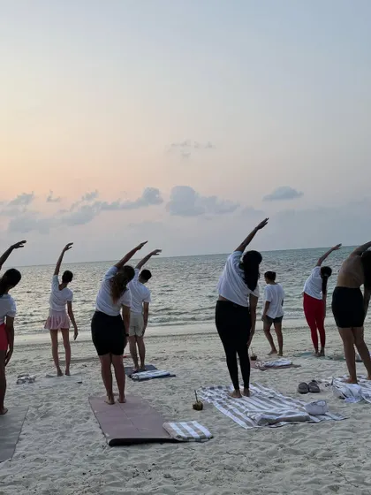 A gentle side stretch during a beach yoga session. Our practices are designed to be restorative, helping you stretch and mobilize your body after a day of diving or exploring.