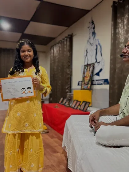 A young yogi, dressed in yellow, receives her certificate of completion. We celebrate the effort and enthusiasm of every child who participates.
