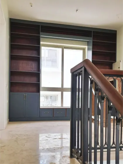 A view of the library from the staircase, showing how it elegantly occupies the landing space, turning a transitional area into a functional and beautiful room.
