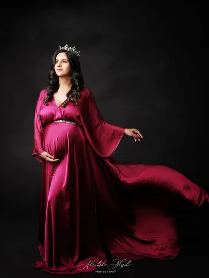 Crowned and draped in luxurious magenta satin, this mother-to-be looks every bit the queen she is.