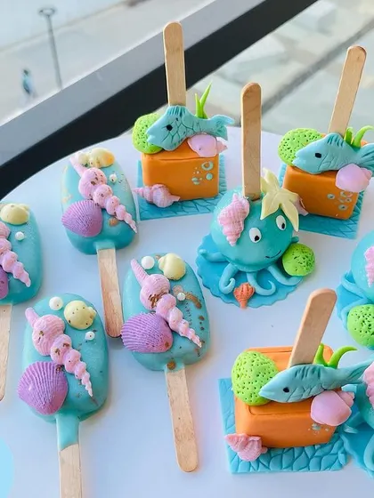 These under-the-sea themed cakesicles were designed as edible party favors. The set includes designs like seashells, octopuses, and fish, all handcrafted to match the mermaid party theme.