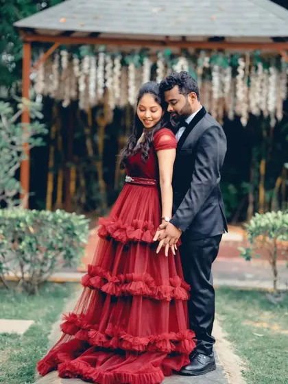 A sweet moment between this couple during their pre-wedding shoot. She is wearing a tiered maroon ruffle gown, perfectly complemented by his classic black tuxedo.