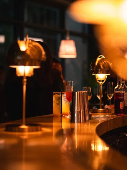 The bar counter, gleaming under soft, warm lights. It’s a place of craft and energy, where cocktails and conversations come to life.