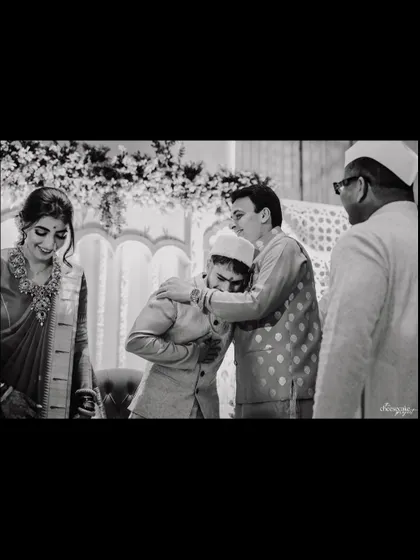 A black and white shot capturing a heartfelt embrace between the groom and his father.