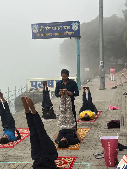 Guiding students in Sarvangasana (shoulder stand), an inversion that calms the nervous system, made even more special by the riverside setting.