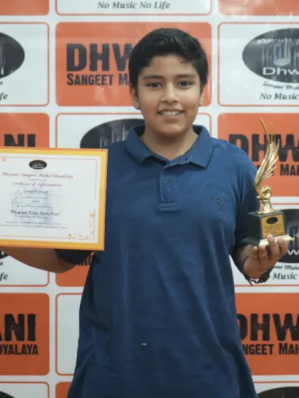 A young drummer proudly holds his certificate and trophy.