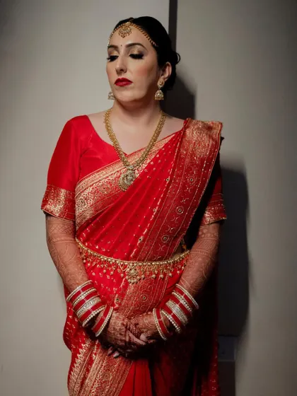 A stunning portrait of the bride in a traditional red saree. The rich colors and her elegant posture exude timeless grace and beauty.