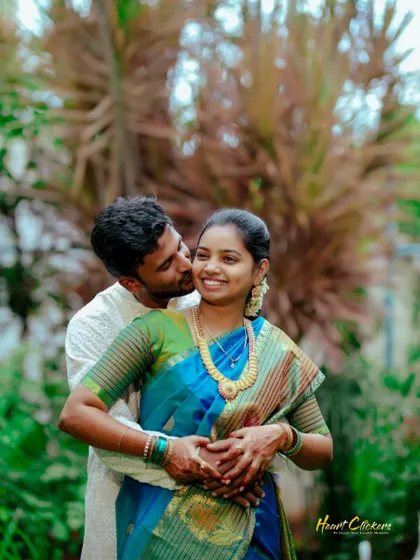 A happy and candid embrace. The lush green background makes the couple's joy and colorful attire stand out.