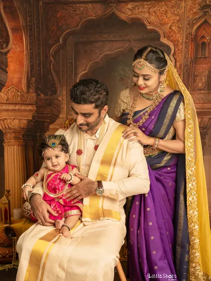 A beautiful family portrait celebrating Krishna Janmashtami. The parents look on lovingly as their little one, dressed as baby Krishna, steals the show.