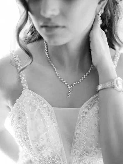 A delicate black and white close-up of the bride's necklace and the intricate beading on her wedding gown.