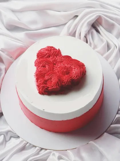 A simple red and white cake with a piped heart on top, perfect for Valentine's Day or an anniversary.
