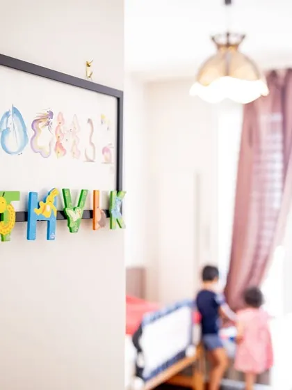 A detail shot of the children's names on their bedroom wall, with them playing in the background. It's these personal touches that make at-home lifestyle photography so meaningful.