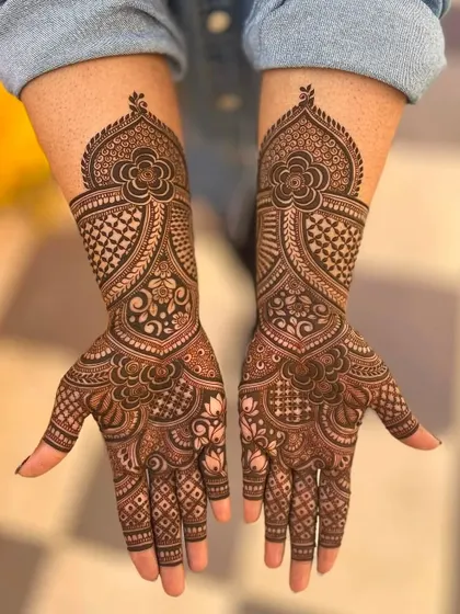 This design features a large floral mandala at the top of the hand, with intricate patterns extending down the fingers. It's a bold and beautiful statement.
