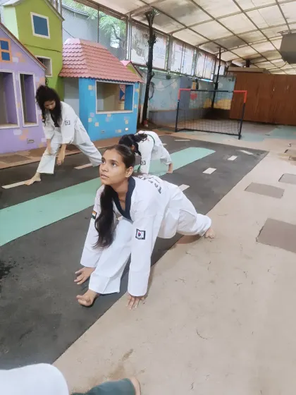 A student holds a deep lunge stretch, focusing on her form. Proper stretching builds a strong and flexible foundation for a martial artist.
