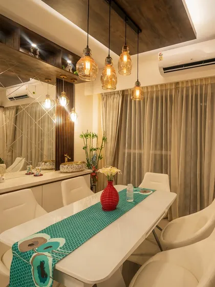 A modern dining space designed for intimate family meals. We used a sleek white dining table, contemporary chairs, and a striking mirrored wall that reflects the warm pendant lighting, making the room feel larger and more vibrant.