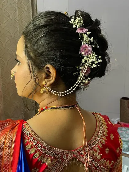 A side profile of the floral bun, showing how it complements the traditional ear chains (kaan vel). Every element is considered for a balanced look.