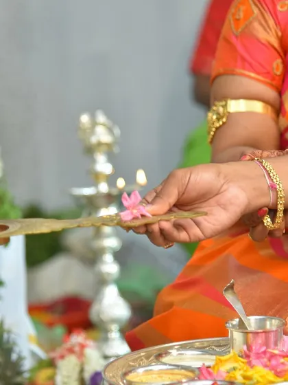 A hand offering a flower to the sacred flame (diya) during an auspicious ceremony. I use lighting to emphasize the warmth and spirituality of these moments.