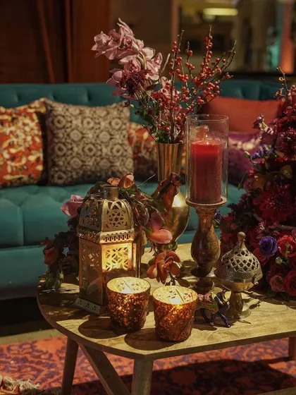 A cozy seating nook within the 'Bazaar', featuring a plush teal sofa, patterned cushions, and a table adorned with a Moroccan lantern and a small floral arrangement. Every corner was a photo-worthy moment.
