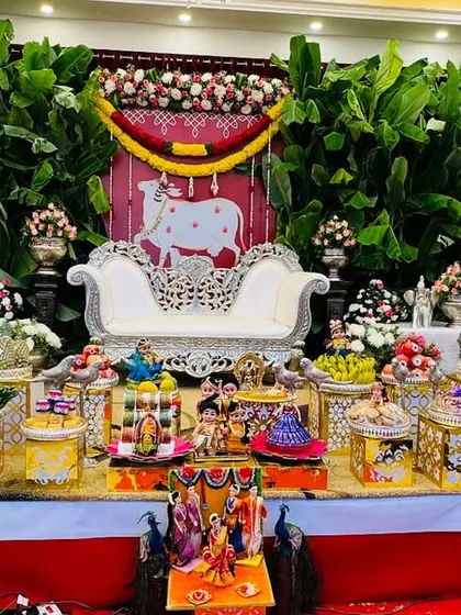 A grand display for a traditional ceremony featuring a cow-themed backdrop. The platters are placed on decorative boxes of varying heights to create a dynamic and visually interesting setup.