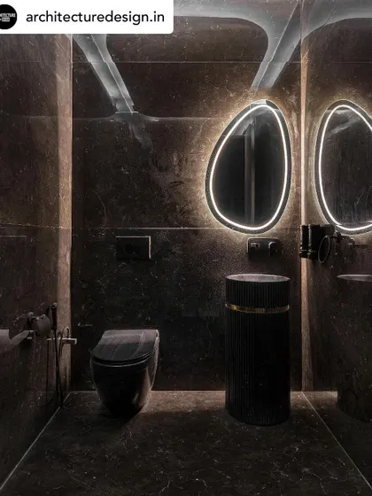 A powder room that makes a statement. We used dark, dramatic marble on the walls and floor, a pedestal sink, and a backlit mirror to create a moody and luxurious atmosphere.