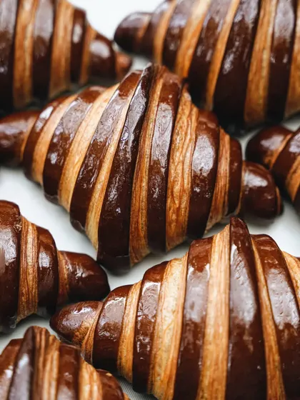 A visually striking pattern of chocolate-striped croissants. This top-down shot creates a graphic, appealing image that highlights the perfect, consistent lamination of the pastry.